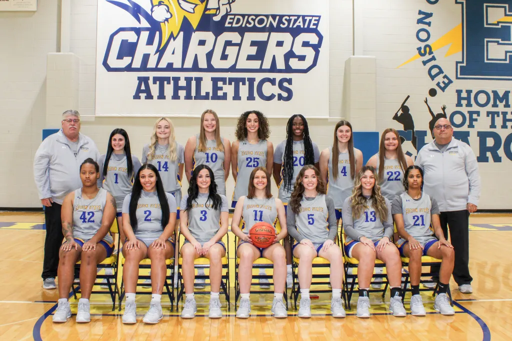 The 2023 women's basketball team and coaches pose in uniform on the basketball court