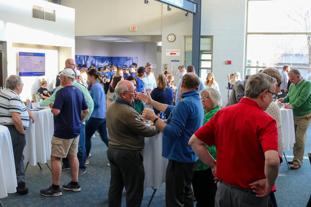 Attendees mingle during the Charger Reverse Raffle community event in the Atrium 