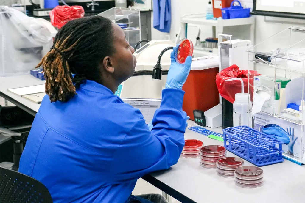 Student in lab coat looking at test samples 