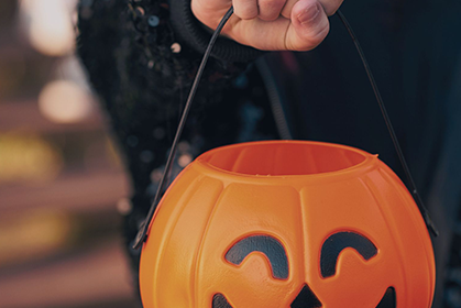 Trick-or-treater holding a pumpkin for candy.