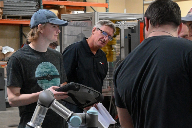 Student and instructor work with a collaborative robotic arm during a manufacturing technology lab session.