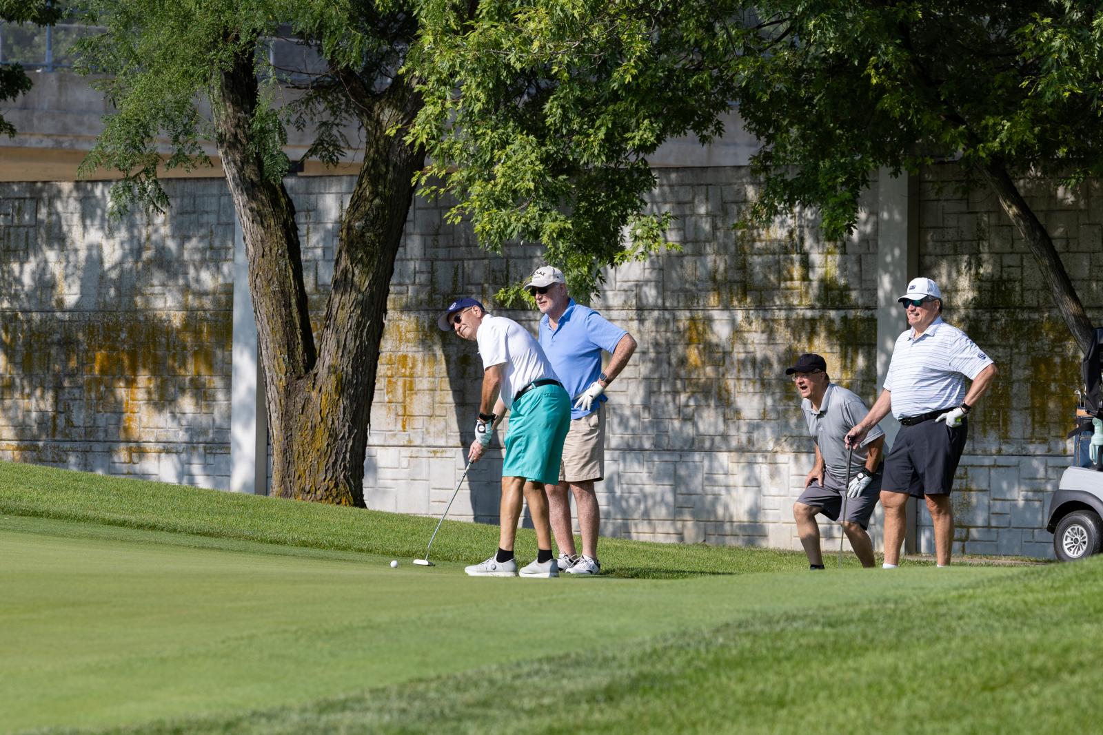 Golfer putts golf ball while friends react behind him