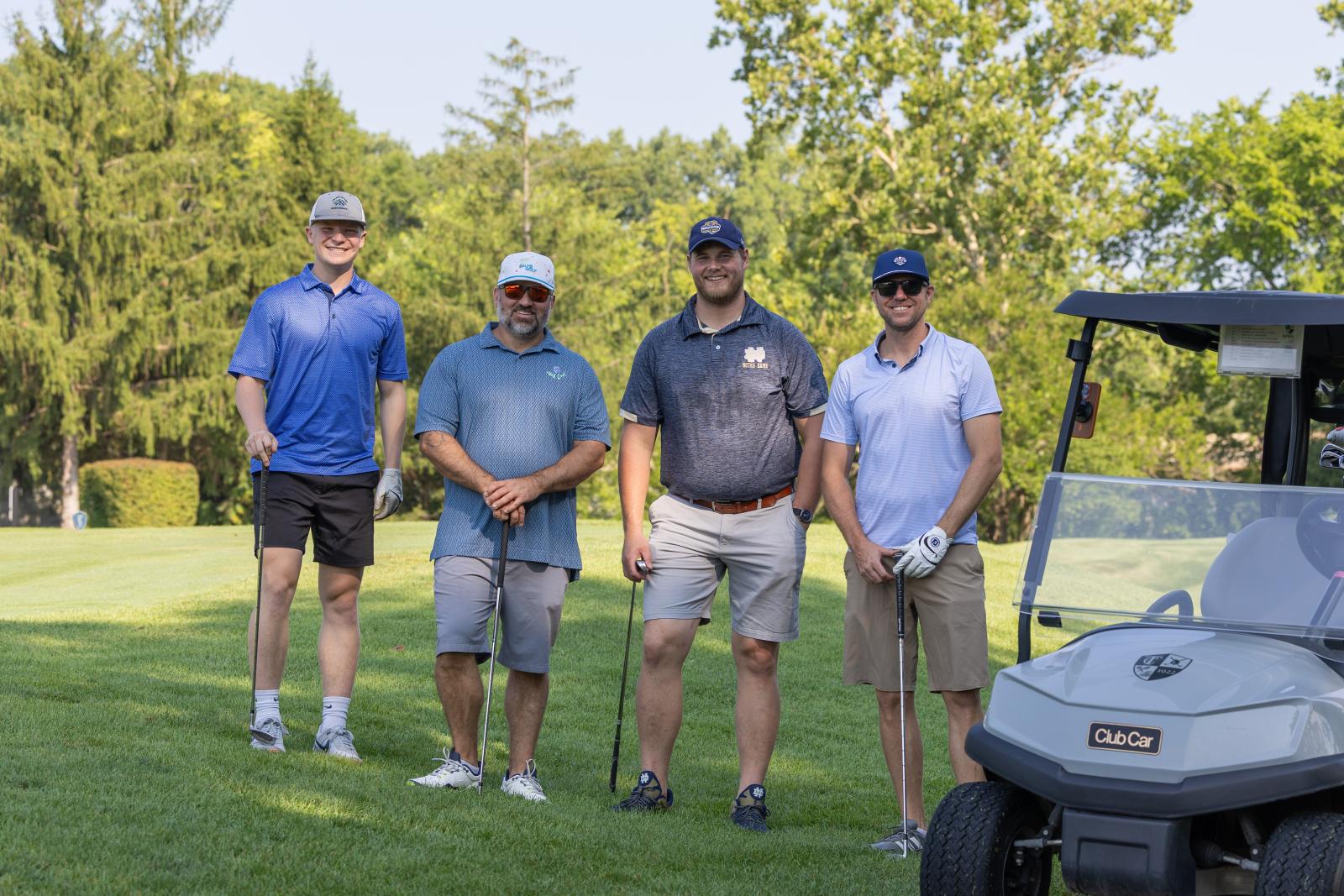 Group of men posing and smiling on the golf course
