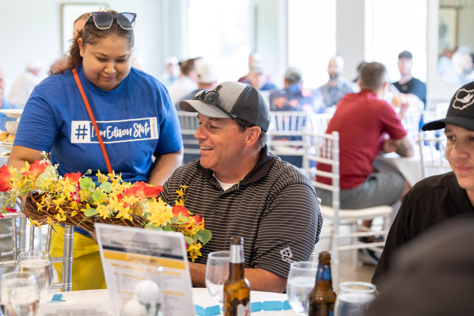 Man receives wreath raffle prize from Edison State student