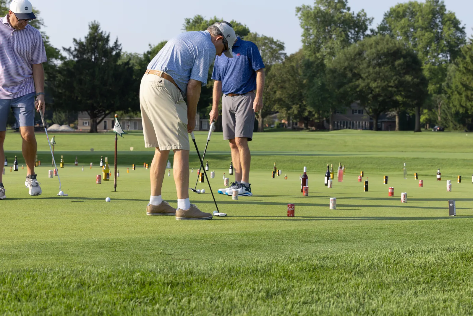 Men putting golf balls around bottled drinks in a game