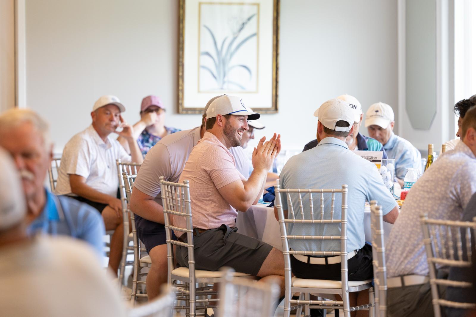 Group of men sitting at a table smiling and clapping